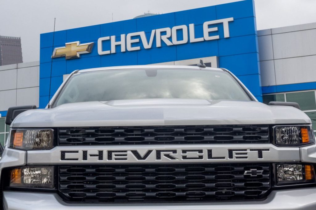 A silver Chevy truck in front of a Chevrolet dealer.