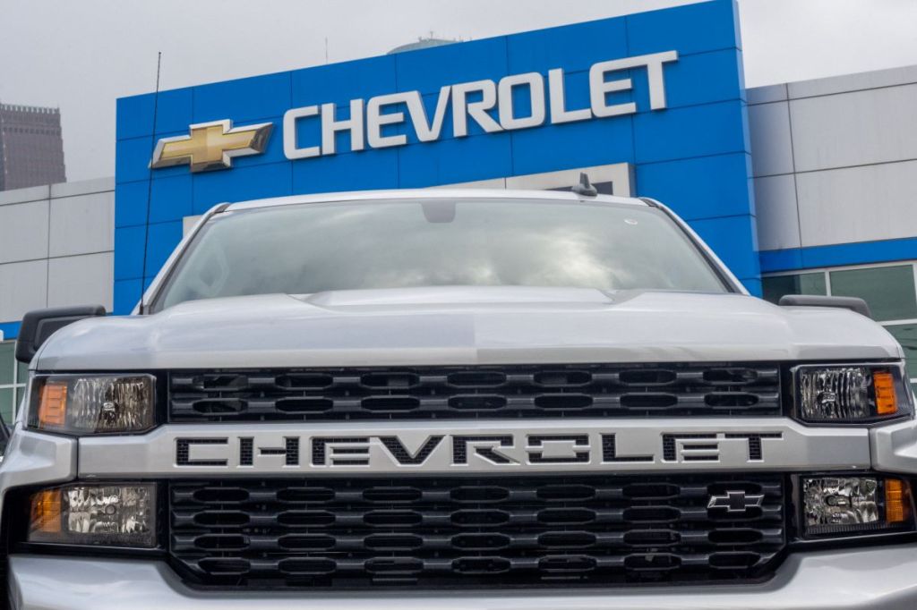 A silver Chevy truck in front of a Chevrolet dealership.