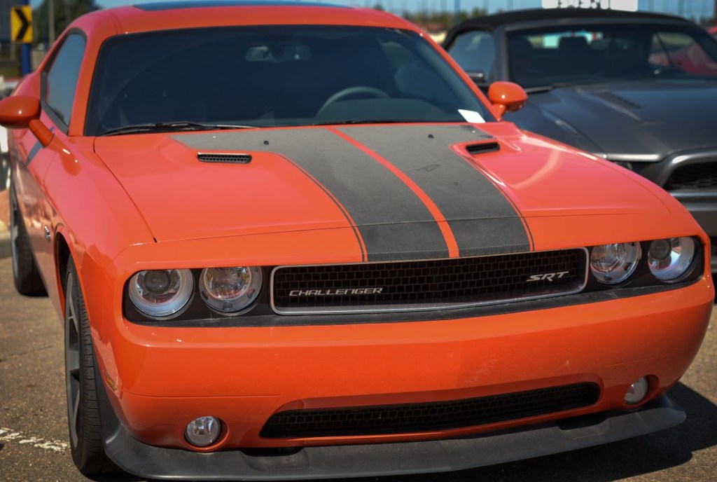 An orange Dodge Challenger with a black stripe down the center. 