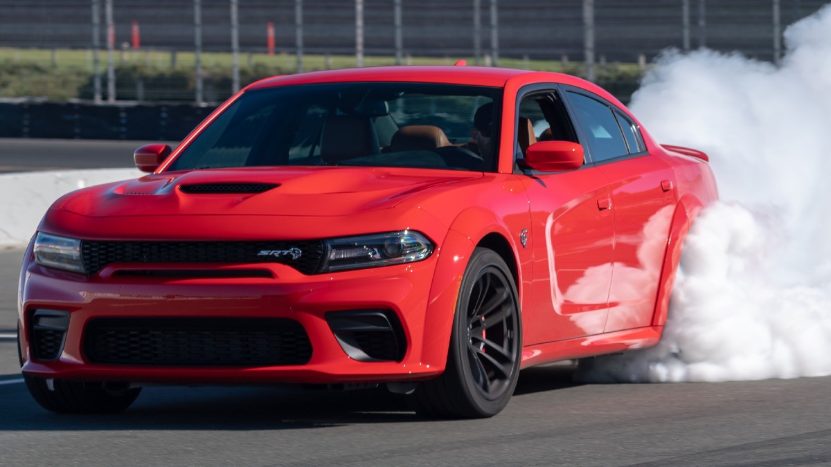 a red dodge charger hellcat doing a burnout showing off the incredible power it can create