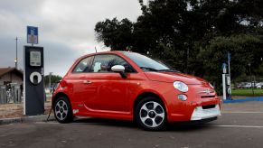 A red Fiat 500e electric vehicle (EV) plugged into a charging station