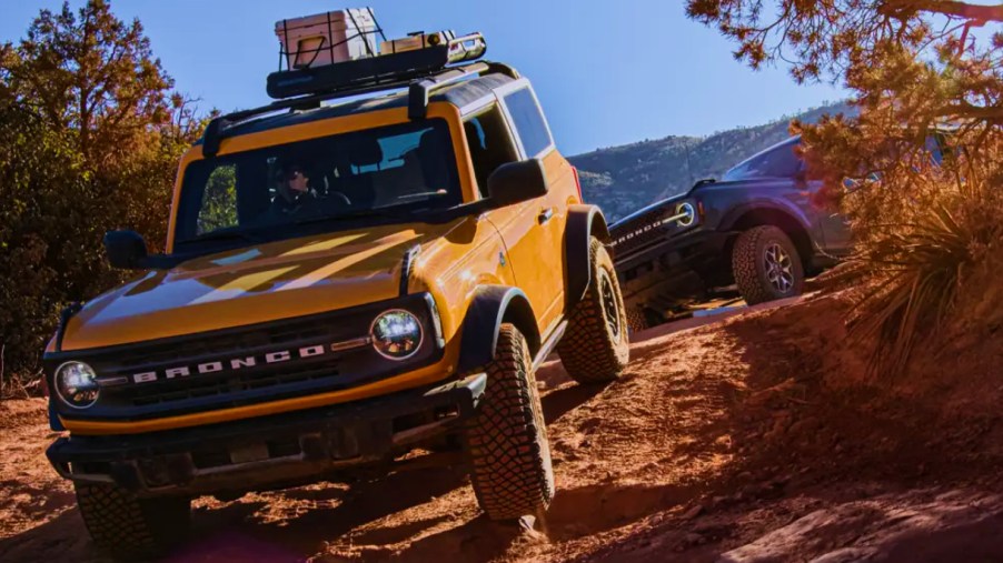 Two Ford Bronco small SUVs are off-roading.