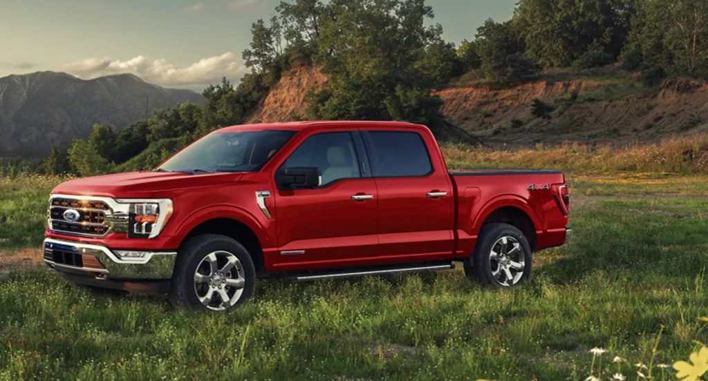 A red 2022 Ford F-150 full-size pickup truck is in a grassy field.