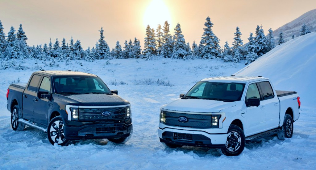 Two 2022 Ford F-150 Lightning electric pickup trucks are parked in the snow. 