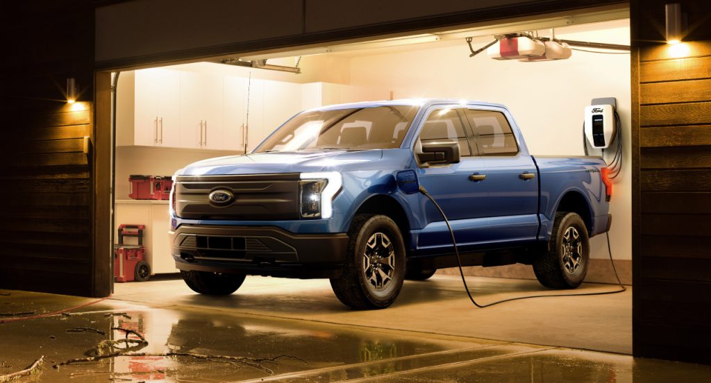 A blue 2022 Ford F-150 Lightning electric pickup truck is parked inside a garage. 