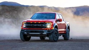 A red Ford F-150 Raptor off-road pickup truck is parked.