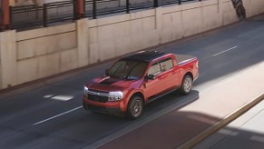 A red 2022 Ford Maverick small pickup truck is driving on the road.