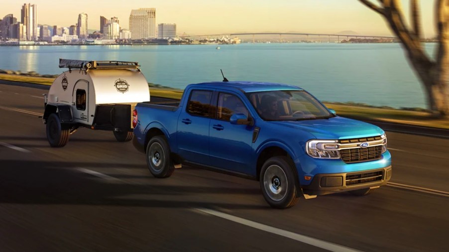A blue 2022 Ford Maverick small pickup truck is towing a small cargo trailer.