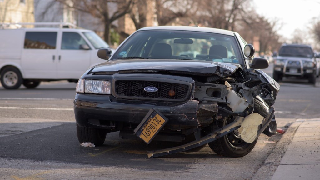 Damaged Ford sedan after a car crash, highlighting the penalties for driving without car insurance in each state