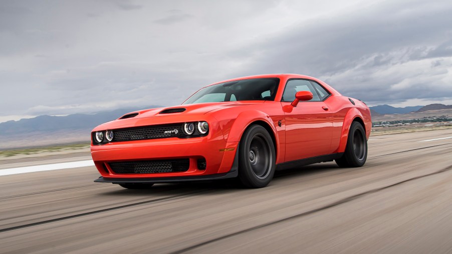 Dodge Challenger muscle car with a front-engine and RWD races down a highway.