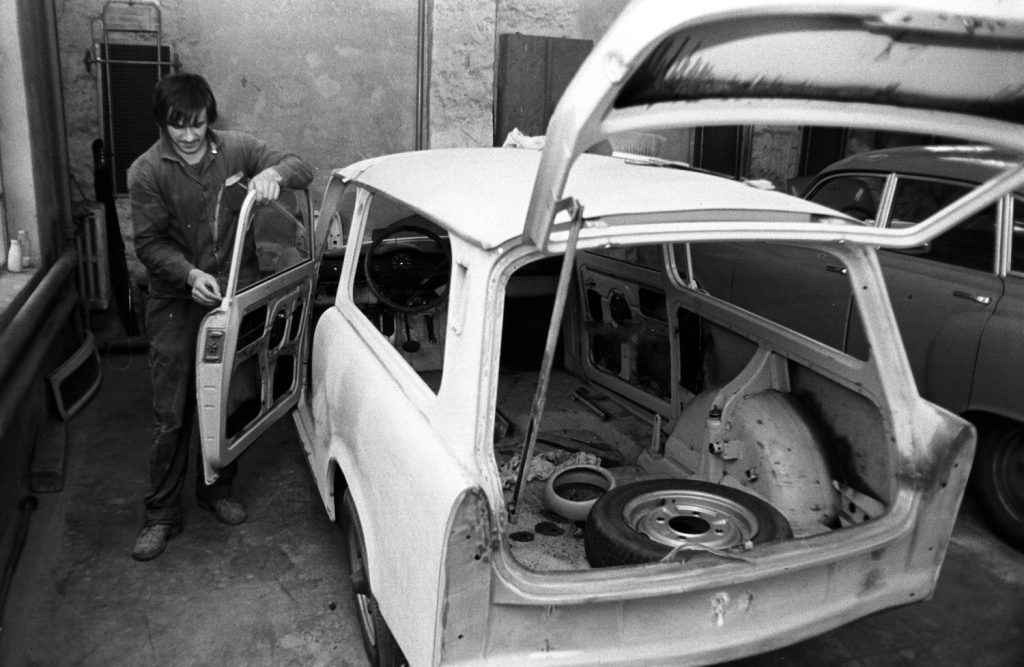 Mechanic removing a car door to be painted.