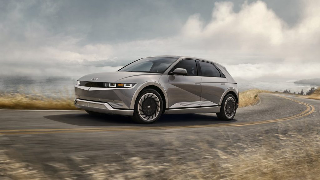 A silver Hyundai Ioniq 5 navigates a beachfront road as an electric SUV.