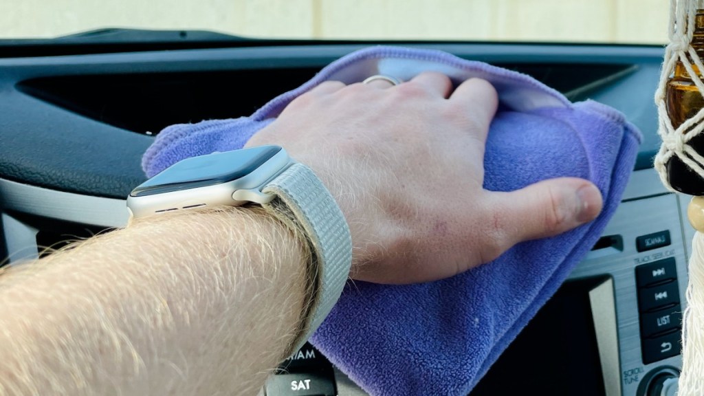A man details his dashboard with a microfiber cloth