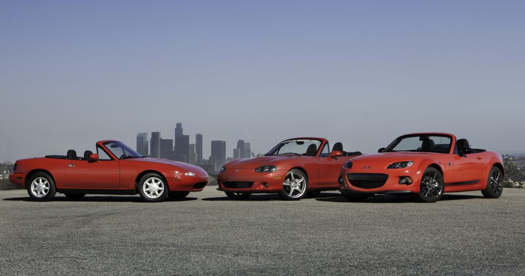 Three red Miata convertibles in front of the Los Angeles skyline at a Mazda car brand meeting.