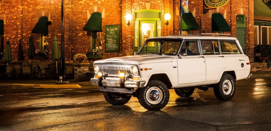 A white 1963 Jeep Wagoneer against a city. A 1980s version is in the new jeep is in "Jurassic World Dominion." 
