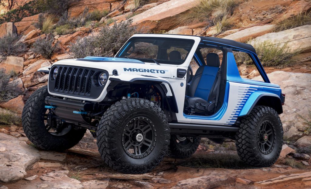 Electric Jeep Wrangler concept vehicle parked in the desert, a rocky slope behind it.