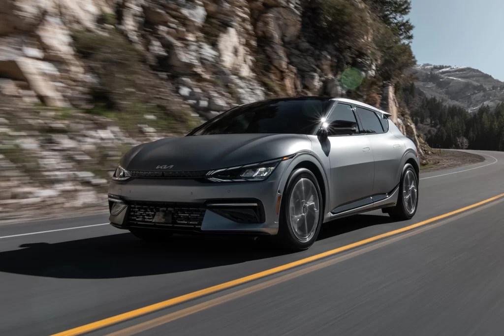 An EV SUV, the Kia EV6 drives on a mountain road.