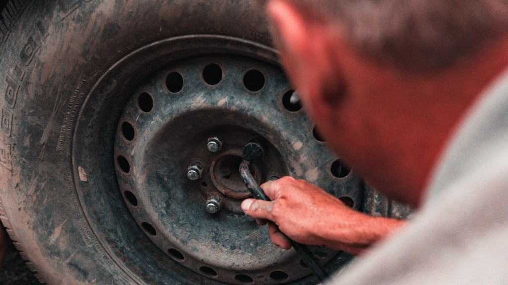 A man loosens the lug nuts on a wheel with a lug nut wrench to service the wheel