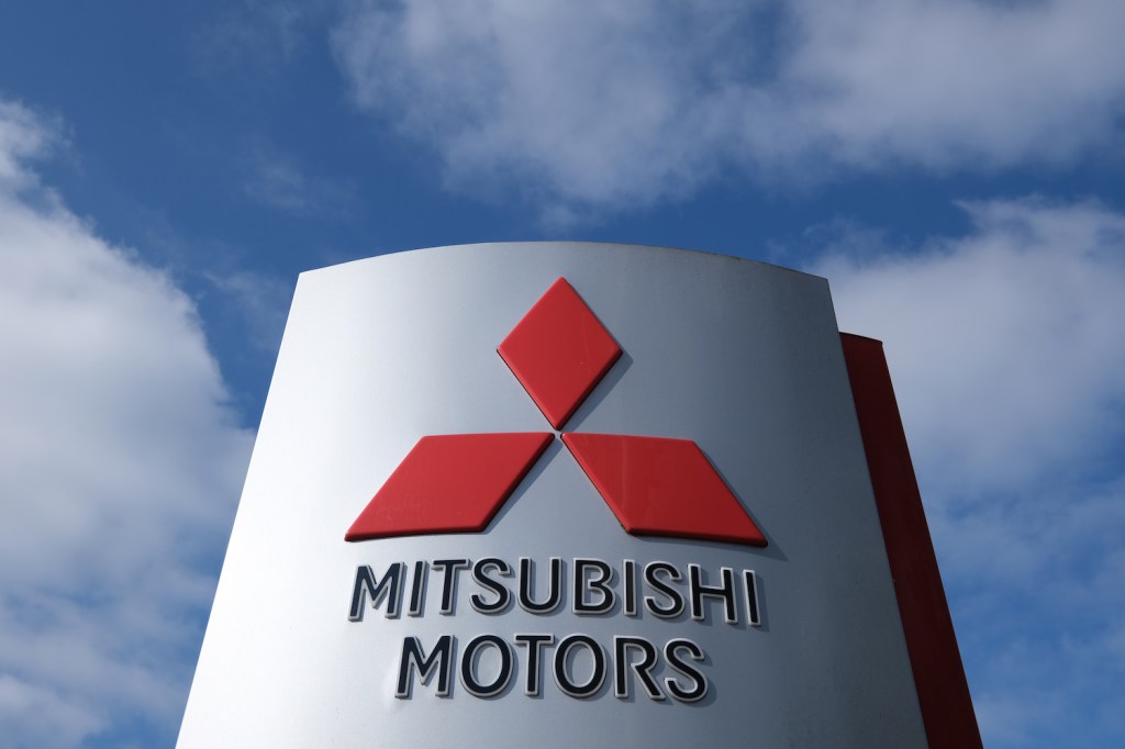 Dealership sign with the Mitsubishi logo against a blue sky.