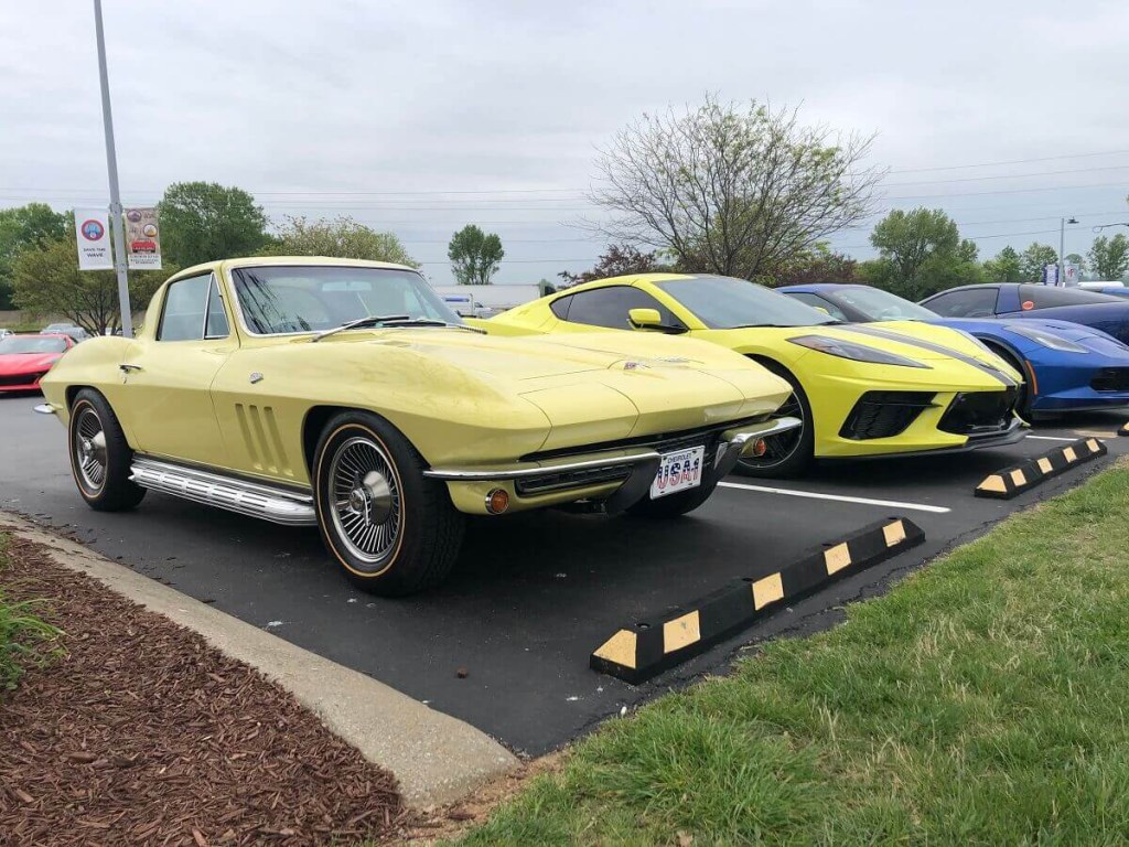 A classic yellow Chevrolet Corvette C2 parks next to much newer Corvette C8. 