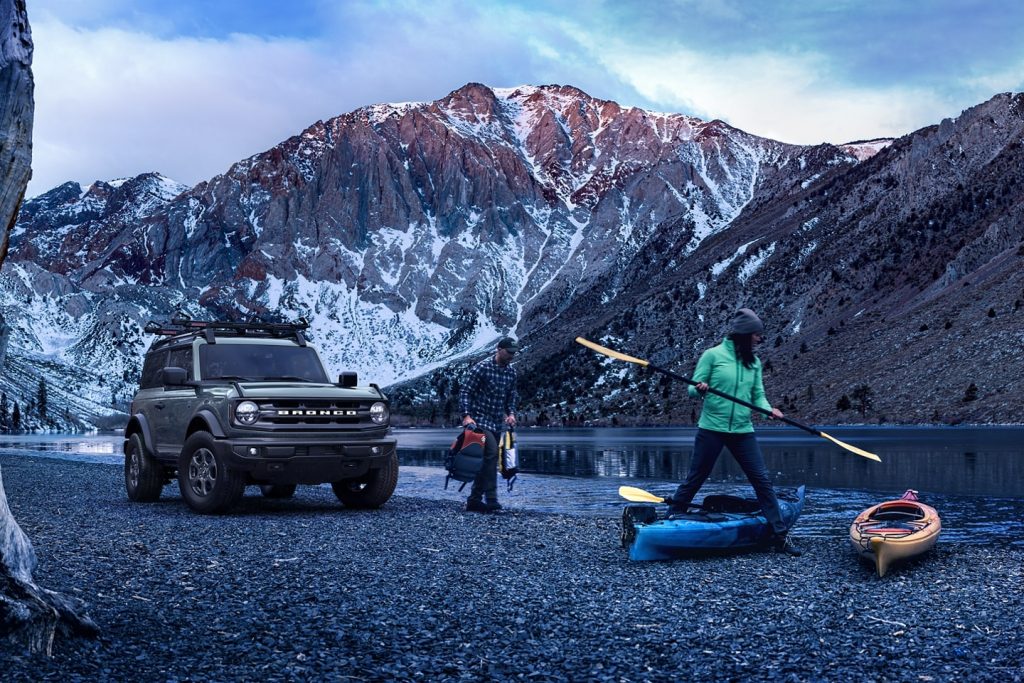 People unloading kayaking gear from a gray 2022 Ford Bronco, an SUV with a high dealer markup