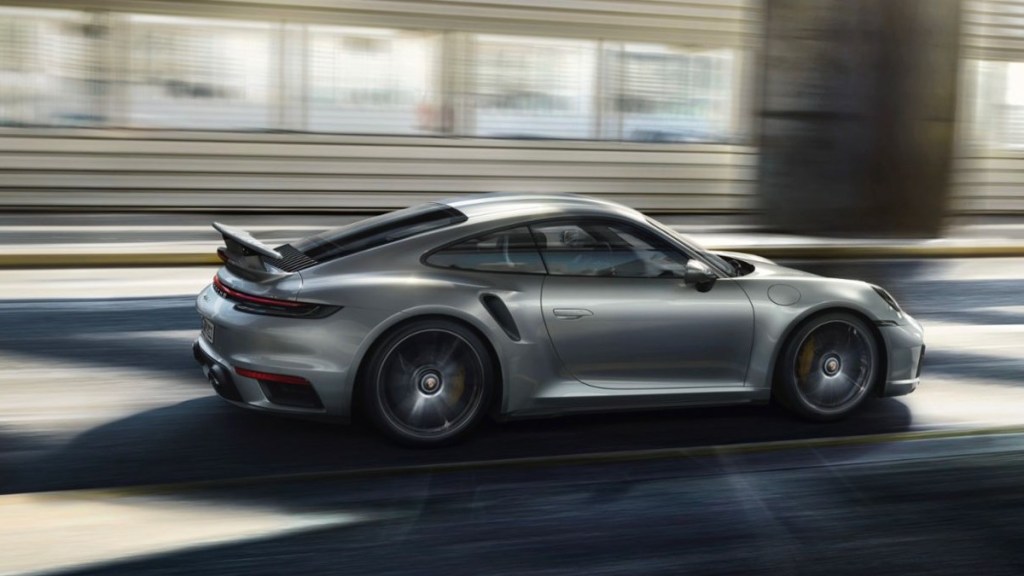 a silver porsche 911 turbo s zooms along a city street displaying its sleek style and top-notch performance