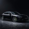 A black 2022 Porsche Panamera 4 E-Hybrid Platinum Edition parked in a dark room with bright lighting brining it into view