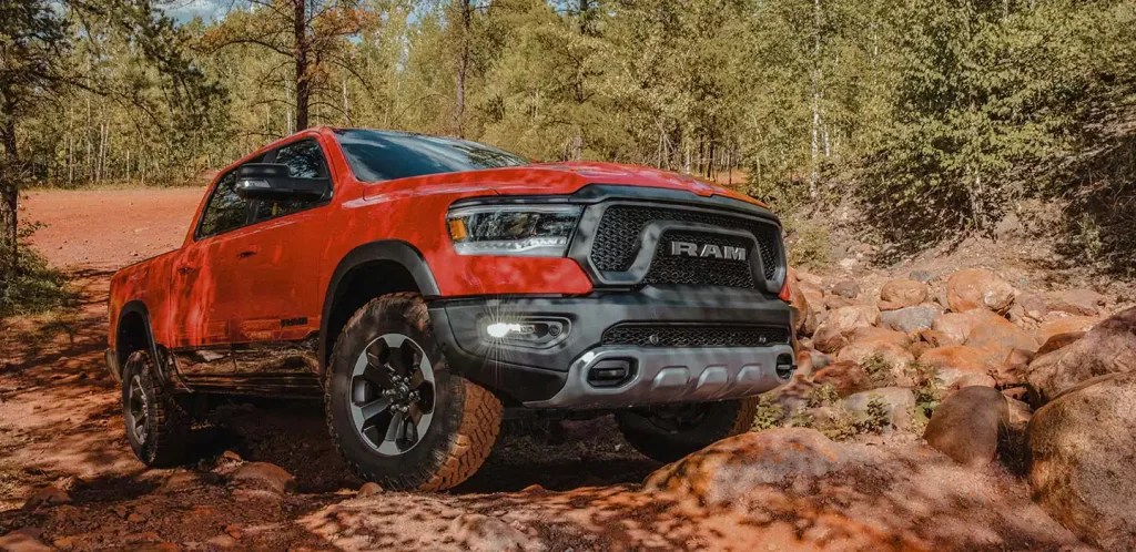 The 2022 Ram 1500 shows off its capability as a full-size pickup truck on a trail, it wears red paint.