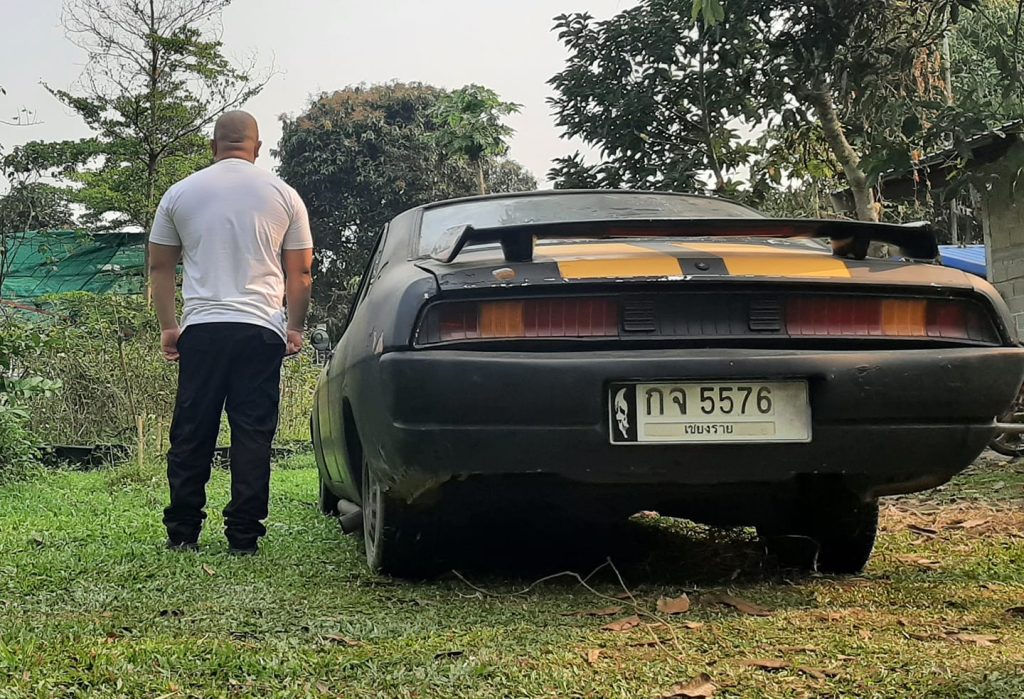 Rear view of Vin Diesel look-alike in Thailand by a Ford Mustang disguised as Fast and Furious Dodge Charger