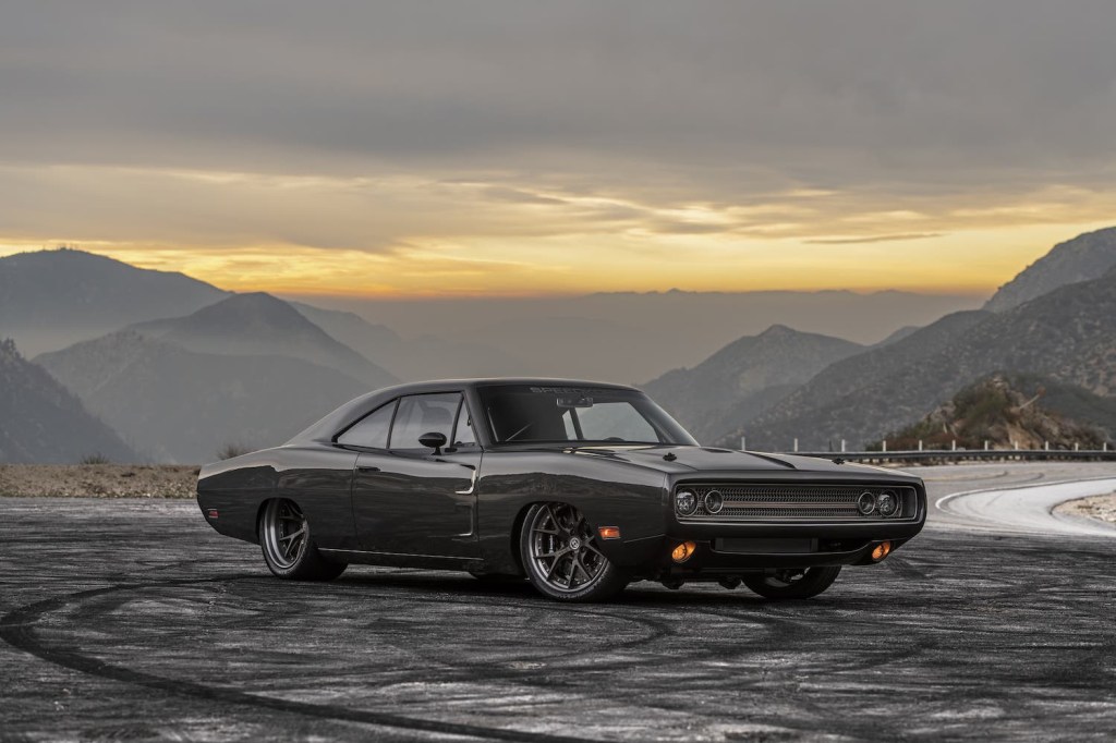 Carbon fiber 1970 Dodge Charger parked on an empty road, a mountain range in the background.