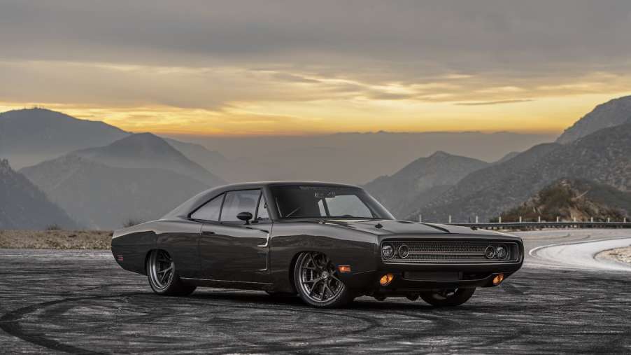 Carbon fiber 1970 Dodge Charger parked on an empty road, a mountain range in the background.
