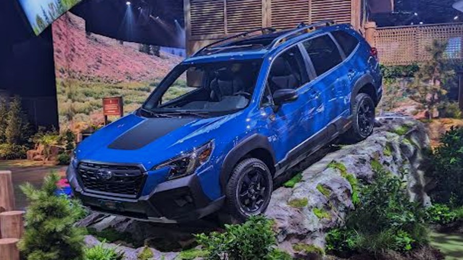 A blue Subaru Forster Wilderness off-road SUV is on a rock at the 2022 New York International Auto Show.