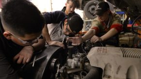 Several teenaged technical school students replace the alternator in a diesel pickup truck