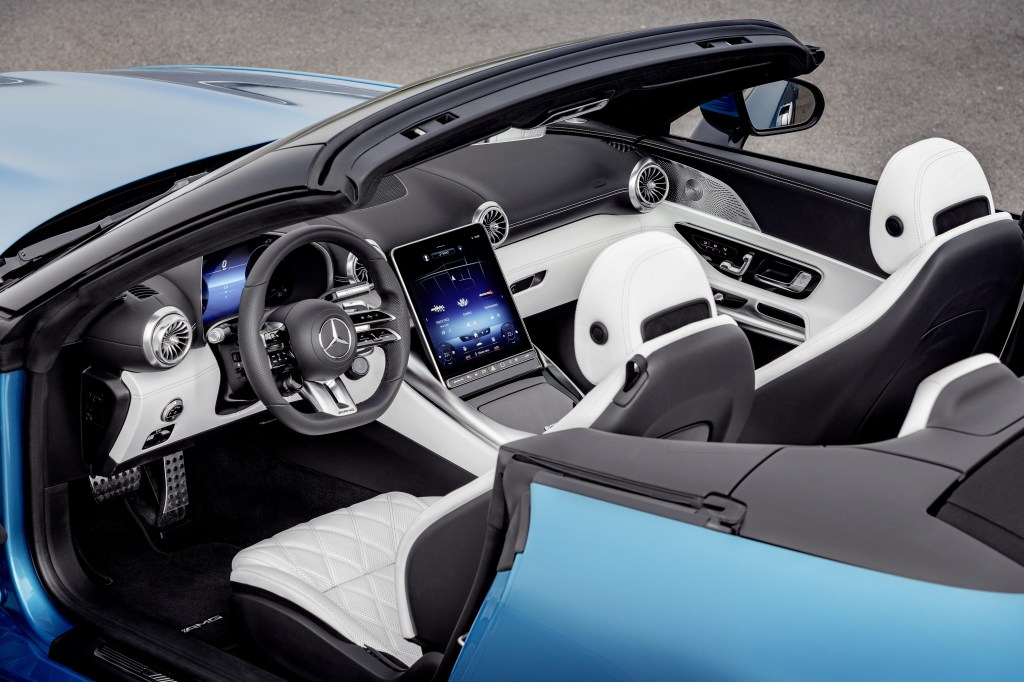 The white-and-black-leather interior of a blue The 2023 Mercedes-AMG SL 43 seen via its open roof