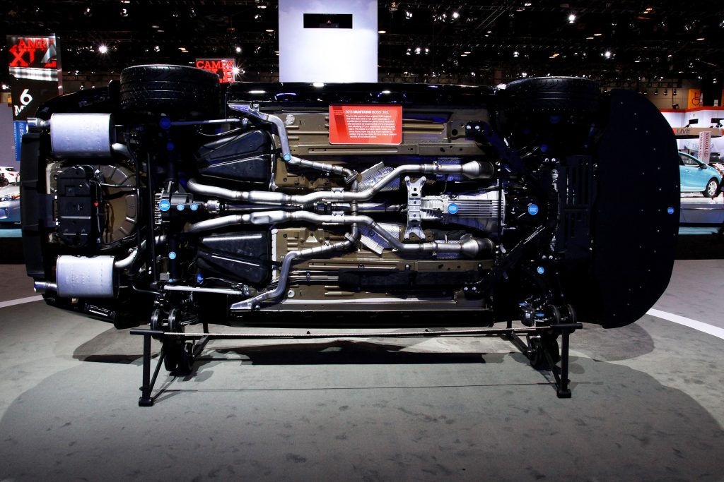 The underside of a black 2013 S197 Ford Mustang Boss 302 showing the drivetrain and suspension at the Chicago Auto Show