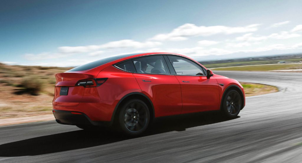 A red 2022 Tesla Model Y electric SUV is driving. 