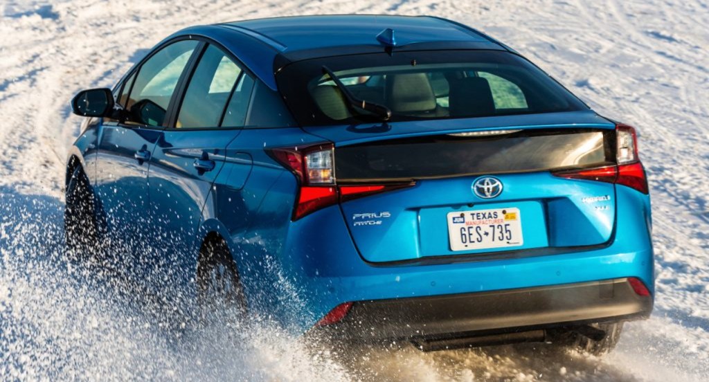 A blue 2021 Toyota Prius hybrid vehicle is driving in the snow. 