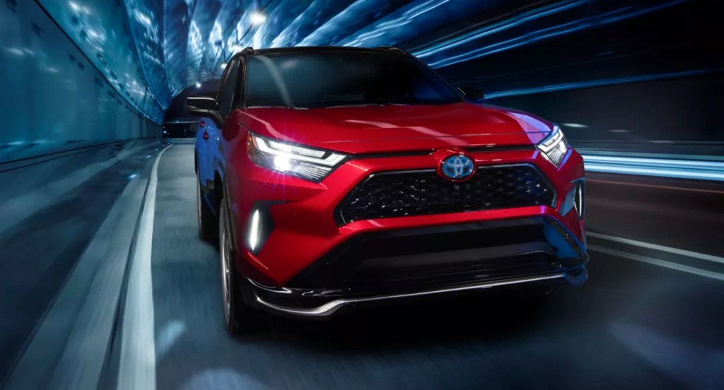 A red 2022 Toyota RAV4 Prime plug-in hybrid SUV is driving.