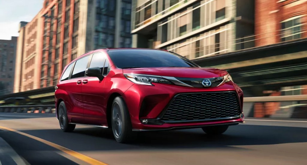 A red 2022 Toyota Sienna minivan is driving on the road. 