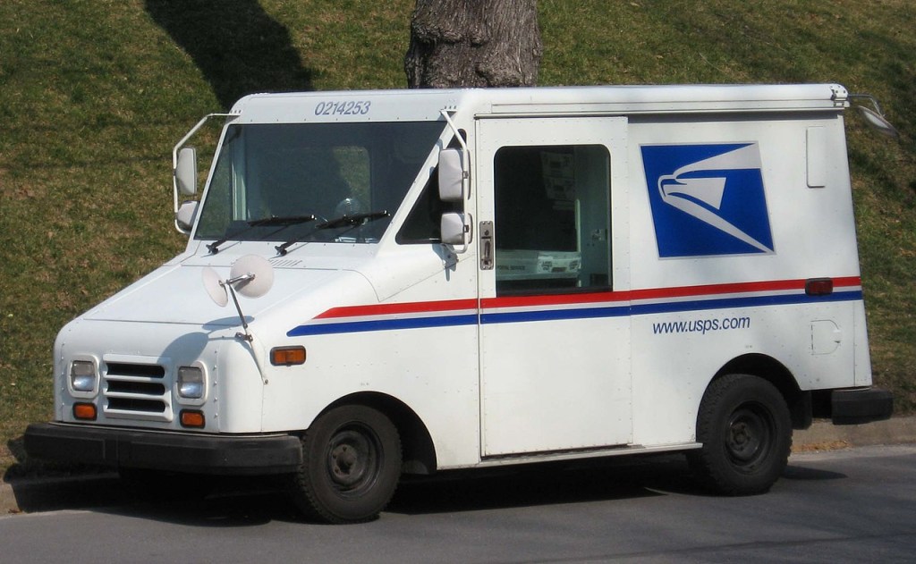 A United States Postal Service mail truck sits outside.