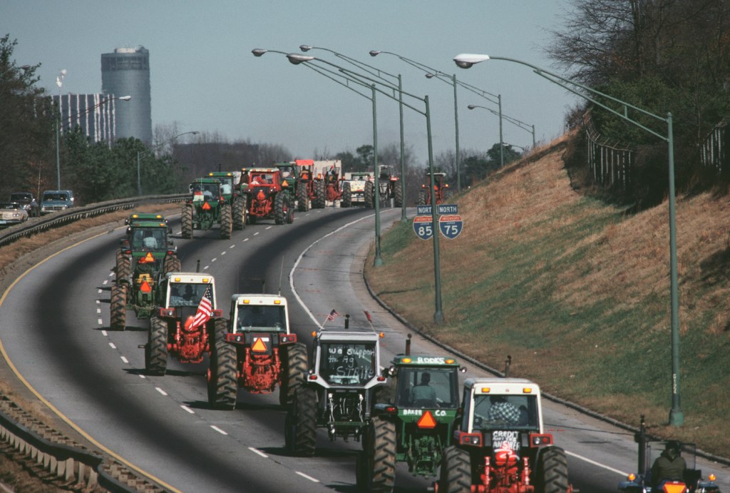 Parade of tractors driving along the highway.