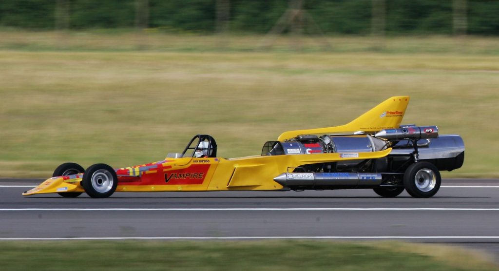 The bright yellow Vampire dragster speeds down a strip