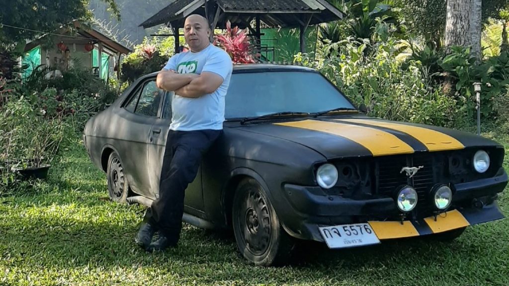 Vin Diesel look-alike in Thailand standing in front of Ford Mustang disguised as Fast and Furious Dodge Charger