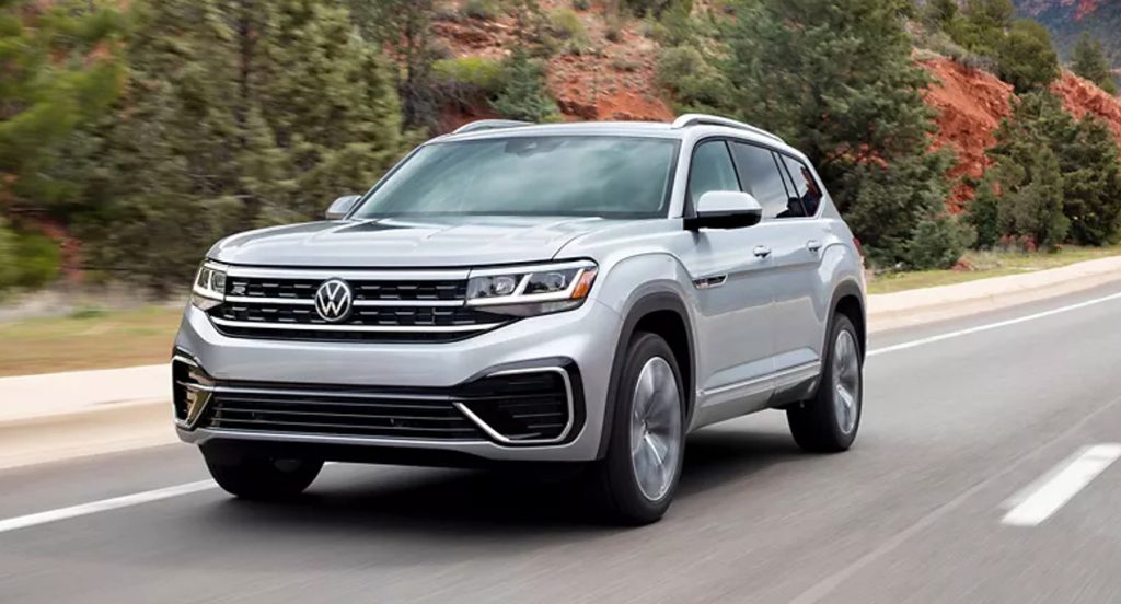 A gray 2022 Volkswagen three-row midsize SUV is driving on the road. 