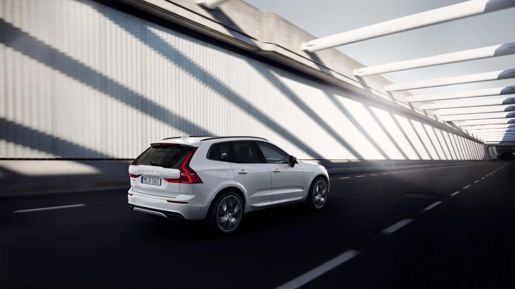 A white 2022 Volvo XC60 navigates an urban environment, it has the Polestar Engineered performance trim.