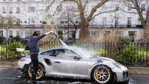Man giving a spring wash to his Porsche 911 GT3RS with a pressure washer and wash bucket
