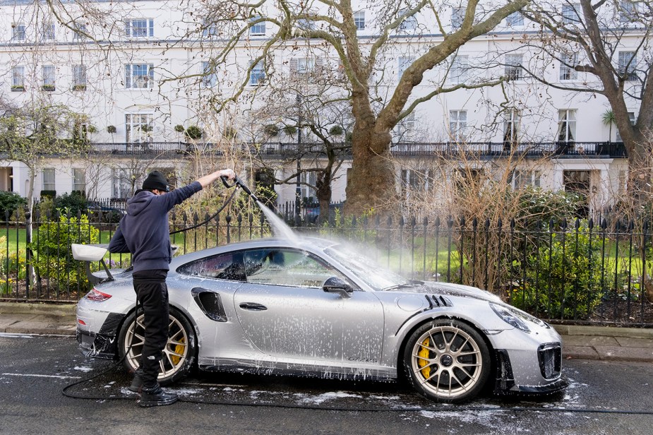 Man giving a spring wash to his Porsche 911 GT3RS with a pressure washer and wash bucket