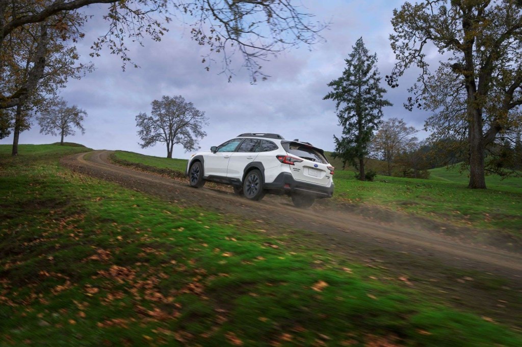 White 2023 Subaru Outback driving up a hill, highlighting its release date and price