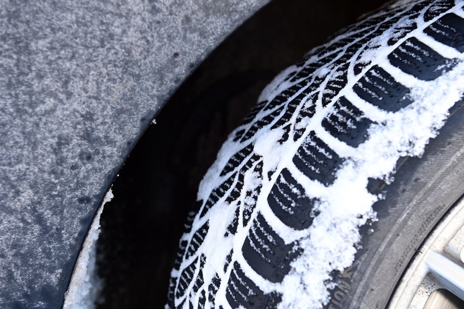 Closeup of winter tires full of snow, demonstrating how they maintain traction via a contact patch extending past the snow