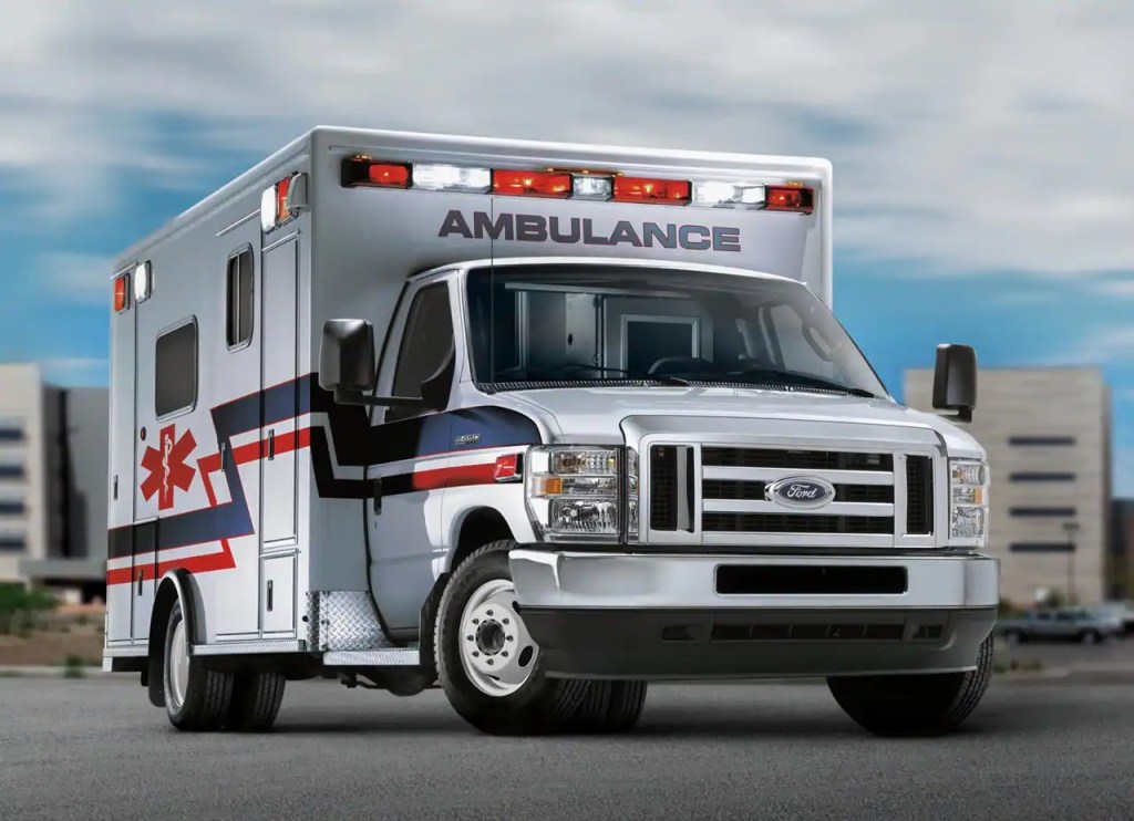 A Ford ambulance in front of a city.
